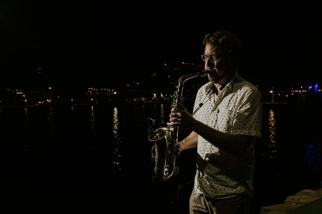 Saxofonista actuando de noche en el puerto de alicante.